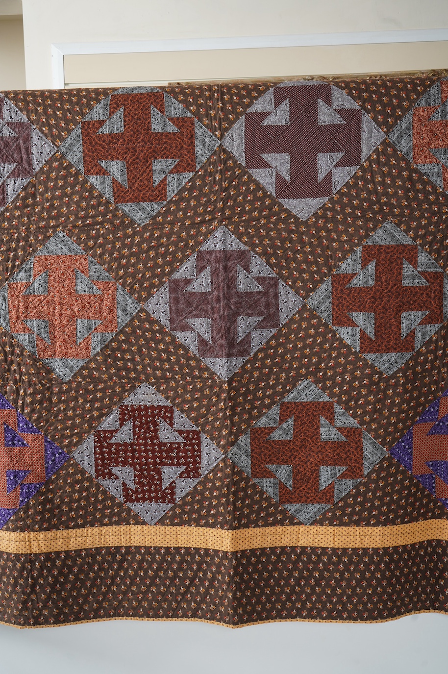 An American Virginian quilt, 1860-1870 (circa American Civil War). Known as a ‘T’ block Virginian style pattern, with a hand pieced and hand quilted front trunk, sold as an unused or washed quilt, designed in brown, red,